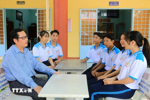Thầy Nguyễn Minh Thiện với các em học sinh Trường Trung học Phổ thông Trà Ôn. (Ảnh: Lê Thúy Hằng/TTXVN)