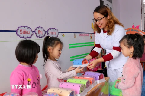 Cô giáo Nguyễn Hà Xuyên cùng học sinh chơi đồ chơi do cô và đồng nghiệp tự tạo. (Ảnh: Minh Thu/TTXVN)