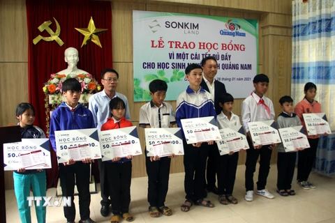 Ông Lê Văn Nhi, Tổng Biên tập Báo Quảng Nam cùng lãnh đạo Công ty SonKim Land trao học bổng cho các em học sinh. (Ảnh: Trịnh Bang Nhiệm/TTXVN)