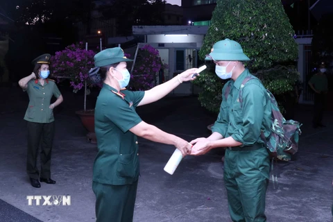 Các thanh niên lên đường nhập ngũ được kiểm tra thân nhiệt, rửa tay sát khuẩn tại điểm giao nhận quân tổ chức tại Quận 5, Thành phố Hồ Chí Minh. (Ảnh: Xuân Khu/TTXVN)