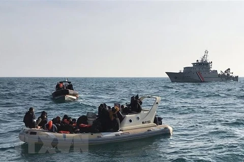 Lực lượng cứu hộ Anh (phía trước) chặn tàu chở người di cư từ Pháp băng qua eo biển Manche. (Ảnh: AFP/TTXVN) 