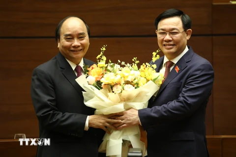 Chủ tịch Quốc hội Vương Đình Huệ chúc mừng Thủ tướng Nguyễn Xuân Phúc hoàn thành xuất sắc nhiệm vụ. (Ảnh: Văn Điệp/TTXVN)