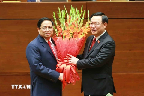 Chủ tịch Quốc hội Vương Đình Huệ tặng hoa chúc mừng Thủ tướng Phạm Minh Chính. (Ảnh: Phương Hoa/TTXVN)