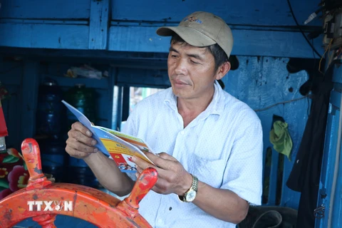 Ngư dân Biện Khắc Linh, thuyền trưởng tàu cá PY 950253, thị xã Đông Hòa đọc thông tin từ sổ tay hướng dẫn bầu cử. (Ảnh: Phạm Cường/TTXVN)