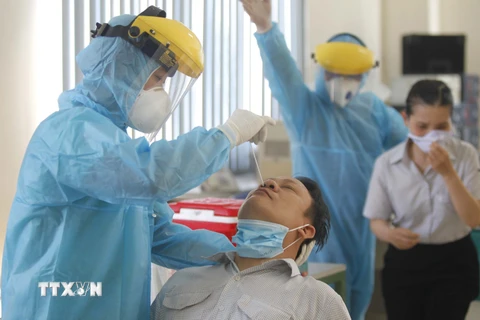 Các y bác sỹ Trung tâm y tế Quận 7 thực hiện xét nghiệm sàng lọc COVID-19 ngẫu nhiên cho công nhân tại Công ty TNHH Kim may Organ Việt Nam. (Ảnh: Thanh Vũ/TTXVN)