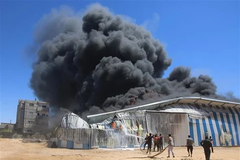 Lính cứu hỏa nỗ lực dập lửa căn nhà bị trúng oanh kích của máy bay Israel tại thành phố Rafah, Dải Gaza. (Ảnh: THX/TTXVN) 