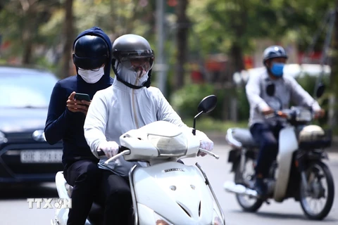 Dưới cái nóng thiêu đốt, người dân tham gia giao thông phải trang bị áo mũ chống nắng kín mít để tránh nắng. (Ảnh: Hoàng Hiếu/TTXVN) 
