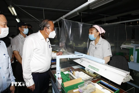 Phó Thủ tướng thường trực Chính phủ Trương Hòa Bình thăm hỏi công nhân tham gia phòng, chống dịch bệnh tại Công ty trách nhiệm hữu hạn Kim may Organ, nơi có khoảng 1.250 lao động, chuyên sản xuất các loại kim may. (Ảnh: Thanh Vũ/TTXVN) 