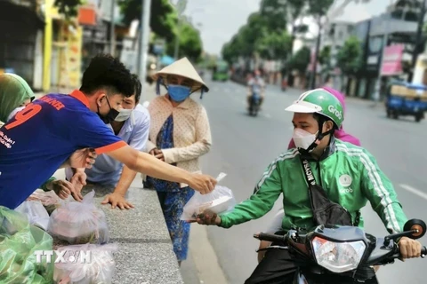 Người dân nhận suất ăn miễn phí từ nhân viên nhà hàng Bò tơ Năm Sánh (quận Gò Vấp, Thành phố Hồ Chí Minh). (Ảnh: Hồng Giang/TTXVN) 