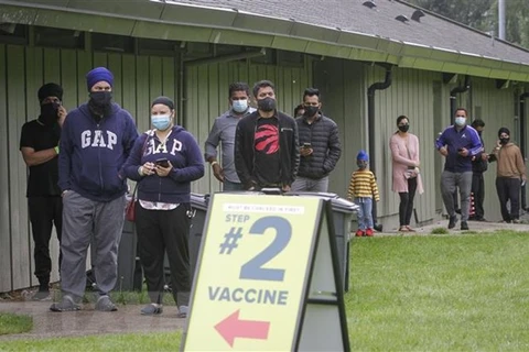 Người dân xếp hàng chờ tiêm vaccine phòng COVID-19 tại Surrey, British Columbia, Canada. (Ảnh: THX/TTXVN)