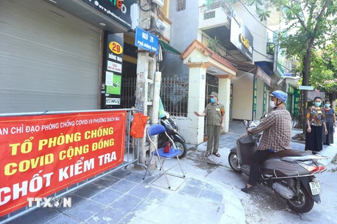 Tổ phòng, chống COVID cộng đồng thuộc tổ dân phố số 5, phường Bạch Mai, quận Hai Bà Trưng kiểm soát người dân ra, vào ngõ 29 Hồng Mai (ảnh chụp sáng 3/8). (Ảnh: Hoàng Hiếu/TTXVN) 