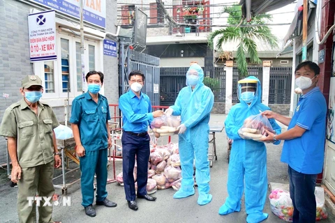 Lãnh đạo Liên đoàn Lao động quận Bình Thạnh, Thành phố Hồ Chí Minh trao quà hỗ trợ cho người lao động tuyến đầu chống dịch COVID-19. (Ảnh: Thanh Vũ/TTXVN)