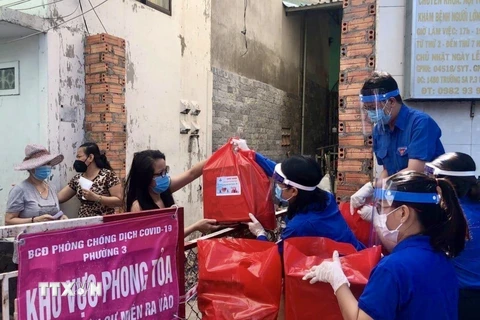 Đoàn viên thanh niên Thành phố Hồ Chí Minh cung cấp nhu yếu phẩm cho những hộ dân thuộc khu vực phong toả tại phường 3, Quận 11. (Ảnh: Hồng Giang/TTXVN) 