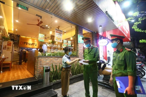 Công an phường Nguyễn Du (Hà Nội) tuyên truyền, nhắc nhở các cửa hàng đóng cửa theo quy định phòng chống dịch COVID-19 (26/3/2020). (Ảnh: Minh Quyết/TTXVN) 