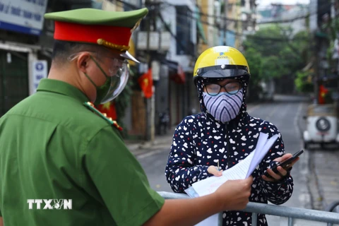 Công an kiểm tra giấy tờ đi đường của người dân phường Chương Dương khu vực được phép ra ngoài khi cần thiết (ảnh chụp sáng 17/8 tại cửa khẩu Cầu Đất). (Ảnh: Hoàng Hiếu/TTXVN) 