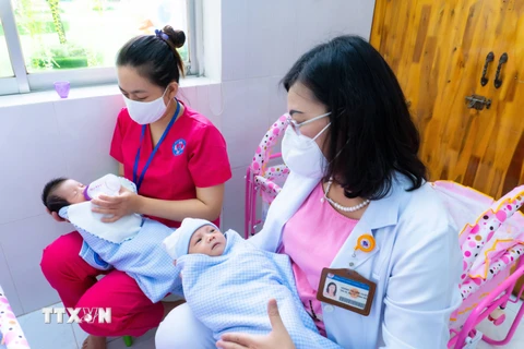 Bảo mẫu và bác sỹ Bệnh viện Hùng Vương cùng chăm sóc trẻ sơ sinh có mẹ mắc COVID-19 chờ người thân đón về. (Ảnh: TTXVN phát)