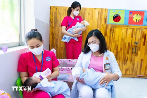 Bảo mẫu và bác sỹ Bệnh viện Hùng Vương cùng chăm sóc trẻ sơ sinh có mẹ mắc COVID-19 chờ người thân đón về. (Ảnh: TTXVN phát) 