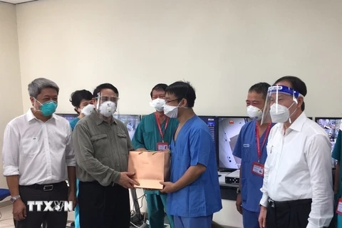 Thủ tướng Phạm Minh Chính tặng quà đội ngũ bác sỹ đang tham gia điều trị bệnh nhân COVID-19 tại bệnh viện dã chiến Hồi sức tích cực ở Bệnh viện quốc tế Becamex tỉnh Bình Dương. (Ảnh: TTXVN) 