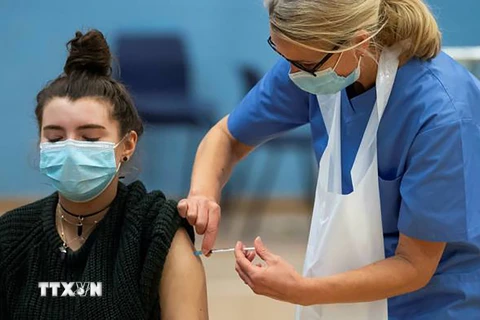 Nhân viên y tế tiêm vaccine ngừa COVID-19 cho người trẻ tuổi ở London, Anh. (Ảnh: Getty Images/TTXVN)