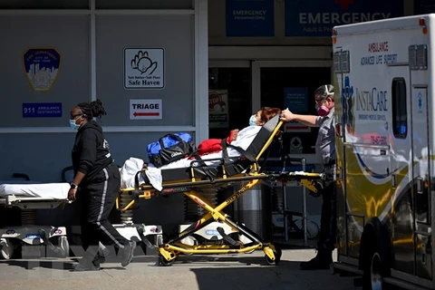 Nhân viên y tế chuyển bệnh nhân COVID-19 tới trung tâm y tế tại New York, Mỹ. (Ảnh: AFP/TTXVN) 