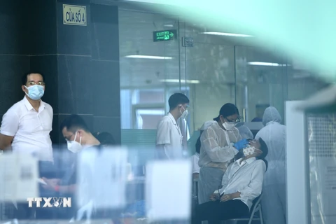 Lực lượng y tế lấy mẫu sàng lọc SARS-CoV-2 cho những người trong tòa D, Bệnh viện Việt Đức chiều 30/9. (Ảnh: Hoàng Hiếu/TTXVN) 