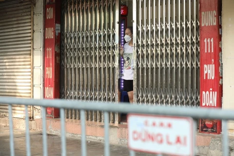 Các hộ dân ở phố Phủ Doãn phía bên ngoài cổng bệnh viện Việt Đức được yêu cầu đóng của và chờ lấy mẫu xét nghiệm. (Ảnh: Minh Quyết/TTXVN)