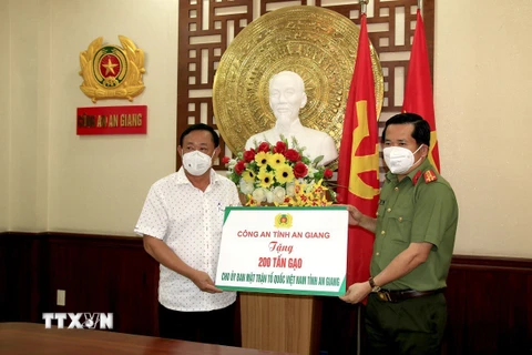 Đại tá Đinh Văn Nơi, Giám đốc Công an tỉnh An Giang (phải) trao biểu trưng tặng 200 tấn gạo cho các bếp ăn tại các khu cách ly tập trung phục vụ người dân từ các tỉnh về quê tự phát. (Ảnh: TTXVN phát)