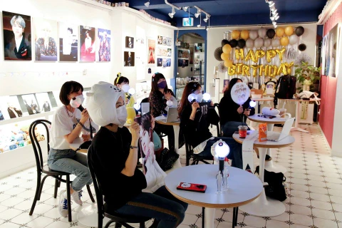 Người hâm mộ Kpop với đèn cổ vũ phát sáng theo dõi buổi hòa nhạc trực tuyến tại một quán càphê của Hàn Quốc. (Nguồn: Reuters) 