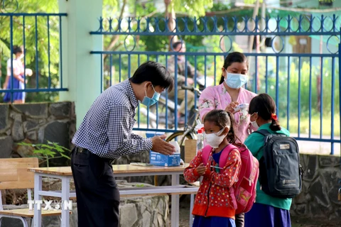 Thầy cô giáo trường Tiểu học và Trung học cơ sở Đông Tiến (xã Đông Tiến), tỉnh Bình Thuận hướng dẫn các em sát khuẩn tay trước khi vào lớp. (Ảnh: Nguyễn Thanh/TTXVN) 