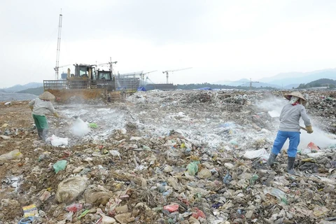 Công ty TNHH MTV Môi trường Đô thị Hà Nội rắc chế phẩm khử mùi tại bãi rác Nam Sơn. (Ảnh: Mạnh Khánh/TTXVN)