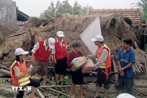 Đại diện chính quyền và Hội Chữ thập đỏ tỉnh Bình Định đến thăm, tặng quà gia đình bà Lê Hưởng (63 tuổi) ở thôn Đông Điền, Phước Thắng (Tuy Phước) bị sập nhà hoàn toàn trong đợt mưa lũ (2003). (Ảnh: Phạm Biết/TTXVN) 