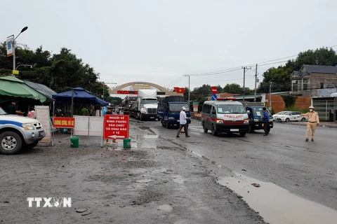 Lực lượng chức năng điều phối giao thông, hướng dẫn người dân vào làm thủ tục khai báo y tế tại chốt Tân Lập, huyện Đồng Phú, tỉnh Bình Phước. (Ảnh: Sỹ Tuyên/TTXVN) 