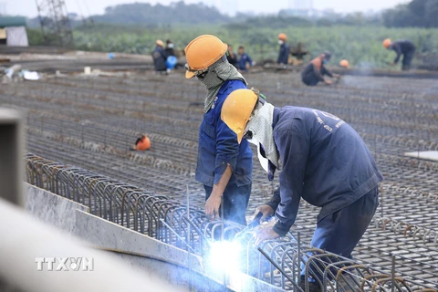 Các công nhân vẫn tiếp tục thi công và đón Tết Dương lịch 2022 ngay trên công trường Cầu Vĩnh Tuy 2. (Ảnh: Hoàng Hiếu/TTXVN) 