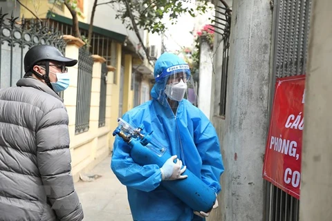 Thành viên Tổ hỗ trợ theo dõi người nhiễm COVID-19 tại nhà phường Lĩnh Nam được trang bị đồ bảo hộ, chở oxy bằng xe máy đến tận nhà người bệnh. (Ảnh: Minh Quyết/TTXVN)