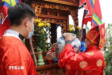 Chủ tế - ông Nguyễn Trọng Thủy, đặt âu gốm đựng nước thiêng lên kiệu để các trai làng rước về đình. (Ảnh: Trung Kiên/TTXVN) 
