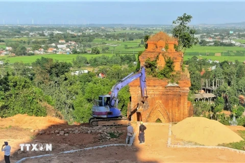 Nhà thầu thi công đưa máy đào vào thi công tại Di tích Tháp Bánh Ít. (Ảnh: TTXVN phát)