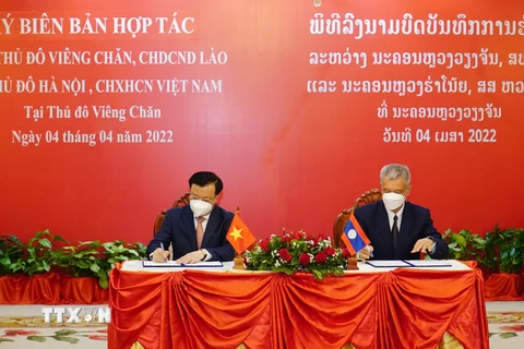Bí thư Thành ủy Hà Nội Đinh Tiến Dũng và Bí thư Thành ủy Vientiane ký kết Biên bản hợp tác giữa hai thành phố Hà Nội và Vientiane. (Ảnh: Phạm Kiên/TTXVN)