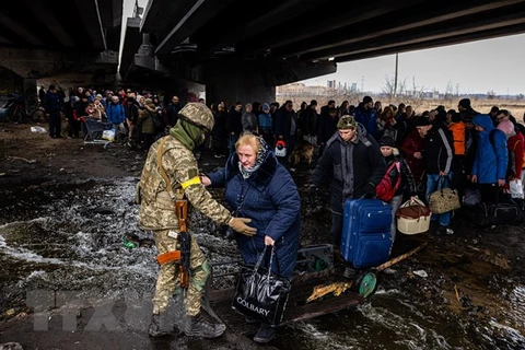 Binh sỹ Ukraine hỗ trợ người sơ tán khỏi thành phố Irpin, phía Tây Bắc thủ đô Kiev. (Ảnh: AFP/TTXVN)