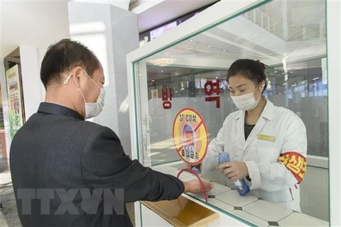 Khử khuẩn tay, đo thân nhiệt, nhằm ngăn chặn sự lây lan của dịch COVID-19 trước khi vào trung tâm thương mại ở Bình Nhưỡng, Triều Tiên. (Ảnh: AFP/TTXVN) 