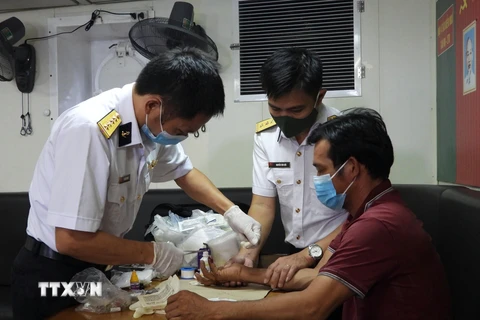 Tổ quân y cứu chữa cho ngư dân Trần Ngọc Toàn (sinh năm 1985, quê quán ở Vạn Giã, Vạn Ninh, Khánh Hòa) bị dập nát đốt 1 ngón tay út của bàn tay phải. (Ảnh: TTXVN phát)