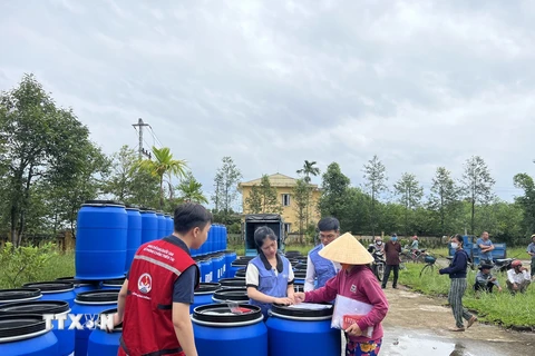 Hỗ trợ thùng nhựa cho các gia đình có nguy cơ chịu ngập lụt do mưa bão ở Thừa Thiên-Huế. (Ảnh: TTXVN phát)