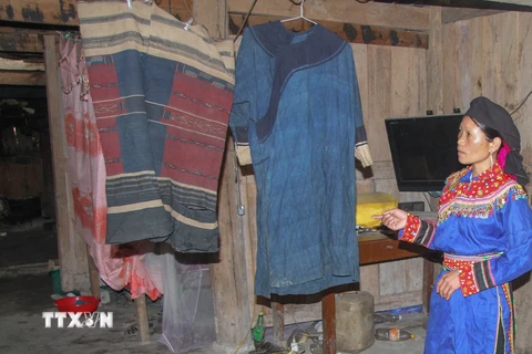 Chị Min Thị Nguyệt giới thiệu về bộ váy áo cổ đã được lưu truyền 16 đời của người Cờ Lao đỏ. (Ảnh: Nam Thái/TTXVN) 