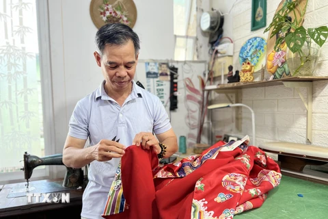 Ông Trần Thanh Tòng hoàn thiện một chiếc áo dài Nhật bình. (Ảnh: Ánh Tuyết/TTXVN)