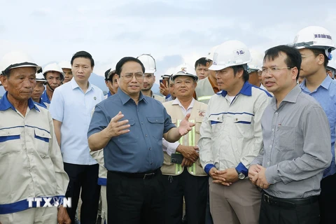 Thủ tướng Phạm Minh Chính nói chuyện với công nhân xây dựng dự án tuyến đường Đông-Tây giai đoạn 1 đoạn từ thành phố Tam Điệp đến huyện Nho Quan. (Ảnh: Dương Giang/TTXVN) 