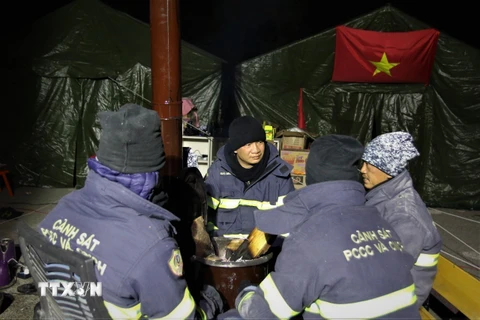 Trung tá Phạm Chí Thành (ngoài cùng, bên phải) cùng đồng đội sưởi ấm ở nơi đóng quân tại thành phố Adiyaman, Thổ Nhĩ Kỳ. (Ảnh: Trường Dụy/TTXVN)