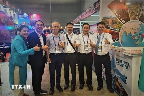 Trưởng đại diện Vietnam Airlines tại Malaysia Hoàng Minh Trí (thứ ba, từ phải sang) chụp ảnh kỷ niệm cùng các đối tác tại quầy hàng. (Ảnh: Hằng Linh/TTXVN)