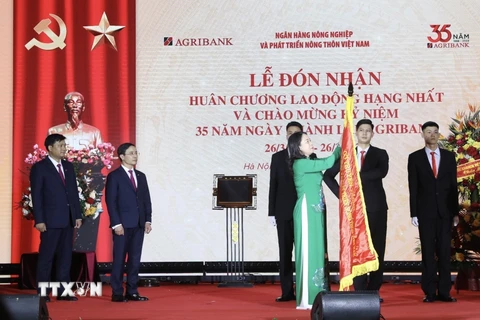 Phó Chủ tịch nước Võ Thị Ánh Xuân gắn Huân chương Lao động hạng Nhất lên lá cờ truyền thống của Ngân hàng Nông nghiệp và Phát triển nông thôn. (Ảnh: Lâm Khánh/TTXVN)