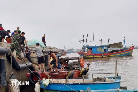 Lực lượng biên phòng và người dân tham gia hỗ trợ, ứng cứu tàu cá gặp nạn. (Ảnh: TTXVN phát)