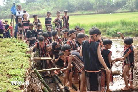 Sau lễ cúng, người dân trong làng cùng xuống giọt nước để thực hiện các nghi thức cầu may mắn. (Ảnh: TTXVN phát) 