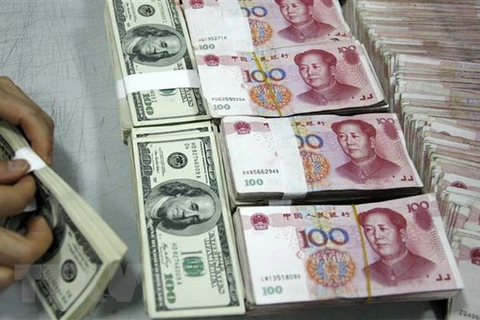 Nhân viên kiểm đồng USD (trái) và đồng nhân dân tệ tại một ngân hàng ở tỉnh An Huy, Trung Quốc. (Ảnh: AFP/TTXVN) 